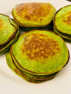 several green pancakes on a white plate