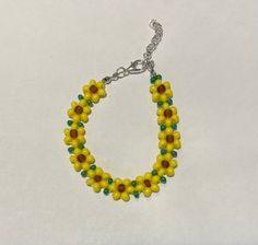 Sunflowers have unique biological clocks that help them follow the sun to soak up the maximum amount of sun rays the days have to offer! Moreover, sunflowers symbolize positivity and joy! This bracelet is a wearable piece of joy, sun rays, and positivity with bright yellows and vibrant green leaves. Lightweight, handcrafted, and made with care, these sunflowers are ready to be added to your collection! Yellow Bohemian Beaded Bracelets For Spring, Yellow Bohemian Flower Bracelets, Yellow Flower Bracelets For The Beach, Yellow Flower Bracelets For Beach, Yellow Flower Bracelet For The Beach, Adjustable Yellow Sunflower Design Jewelry, Handmade Flower Beaded Bracelets For Summer, Summer Festival Flower Bracelets, Summer Flower Beaded Bracelets