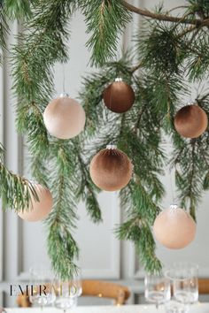 christmas ornaments hanging from the branches of a pine tree in front of a dining room table