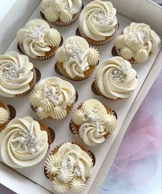 twelve cupcakes with white frosting in a box