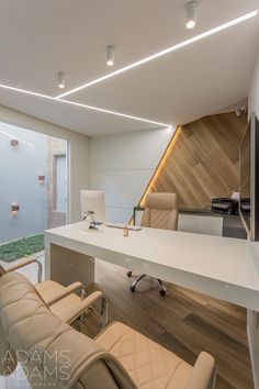 an office with white desks and chairs in front of a large glass window that looks out onto the outdoors