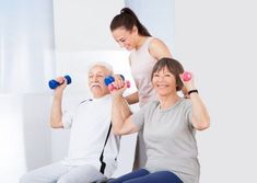 two women and an older man doing exercises with dumbbells while sitting on a chair