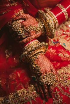 the brides hands are adorned with gold and red jewelry