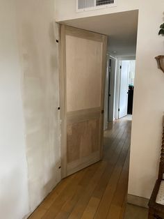 an empty room with a wooden door and hard wood flooring on the side walk