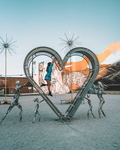 a woman standing on top of a giant metal heart