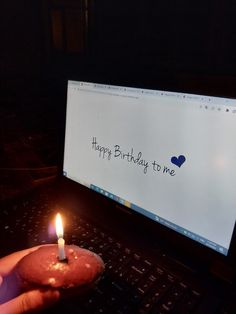 a person holding a donut in front of a computer screen with a birthday card on it