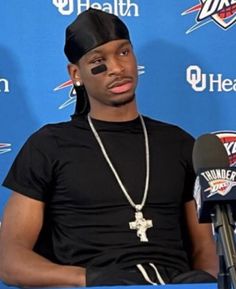 a man sitting in front of a microphone wearing a black shirt and headgear