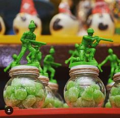 green candies in glass jars with toy army men on the top one is filled with candy