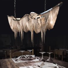 a chandelier hanging over a table with plates and silverware on the table