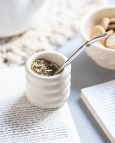 a spoon in a small cup on top of an open book