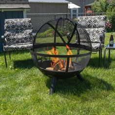 a fire pit sitting on top of a lush green field next to two lawn chairs