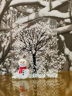 a glass block with a snowman next to a tree