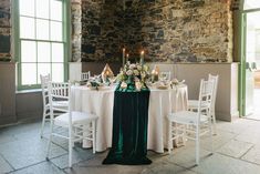 the table is set with white linens and red flowers