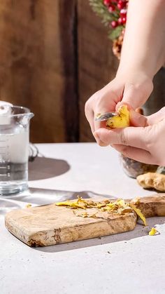 a person is peeling an orange peel on a cutting board next to some other food