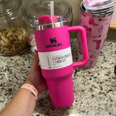 a person holding a pink coffee mug in front of some nuts on the counter top