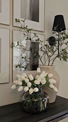 a vase filled with white flowers sitting on top of a wooden table next to pictures