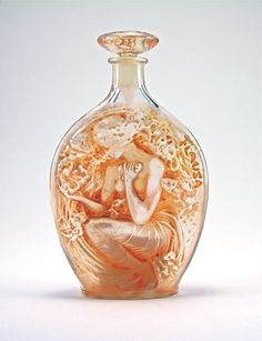 an orange glass vase with a woman sitting on it