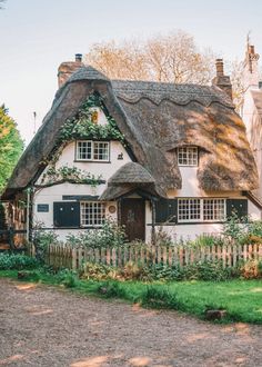 a white house with a thatched roof and black shutters on the front door