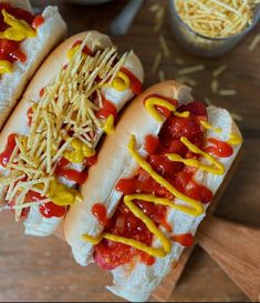 two hot dogs covered in ketchup, mustard and relish sitting on a cutting board