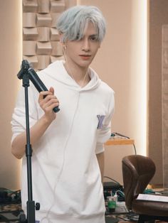 a man with blue hair holding a microphone in front of a recording equipment set up