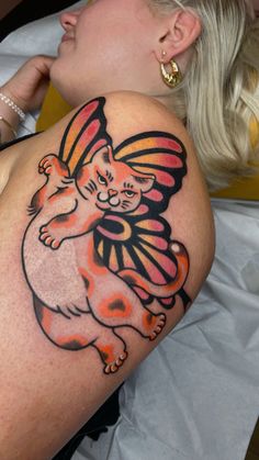 a woman laying on top of a bed with a cat tattoo on her arm and leg