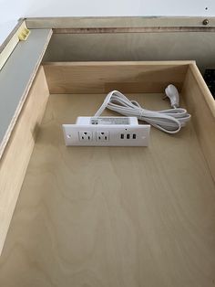 an electrical device is plugged into the side of a wooden box with wires in it