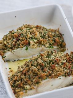 two fish fillets in a white dish with seasoning on the top and bottom