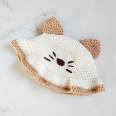 a crocheted hat with a cat's face on it sitting on a marble surface