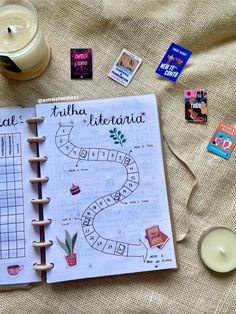 an open notebook sitting on top of a bed next to a candle and some stickers