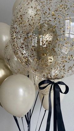 some balloons that are in the air with gold and white confetti on them