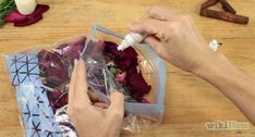 someone is wrapping flowers in plastic bags on a wooden table with candles and other decorations