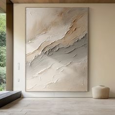 an abstract painting hangs on the wall next to a bench in front of a window