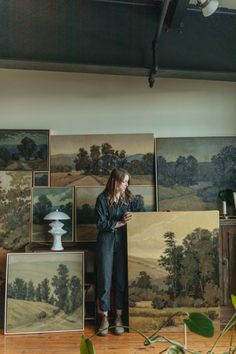 a woman standing in front of some paintings