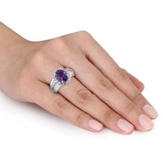 Add a dash of royalty to your attire with this stunning Amethyst and Created White Sapphire Halo Wide Band Ring. Crafted in glittering sterling silver, it features an oval-cut, prong-set amethyst gemstone (10 x 8mm) at the center with a halo of 30 round-cut, prong and pave-set created white sapphire gemstones studded on both the sides of the wide band. This broad band with a sparkling gemstone line creates an unique and shining piece, which draws immediate attention. Buffed with luster, this gor Dazzling Jewelry With Gemstone Accents, Fine Jewelry With Center Stone, Purple Oval Jewelry With Diamond Accents, Silver Oval Amethyst Ring With Gemstone Accents, Oval Silver Amethyst Ring With Gemstone Accents, Dazzling Purple Jewelry With Diamond Accents, Elegant Lavender Jewelry With Center Stone, Formal Purple Jewelry With Diamond Accents, Elegant Amethyst Birthstone Ring In Cubic Zirconia