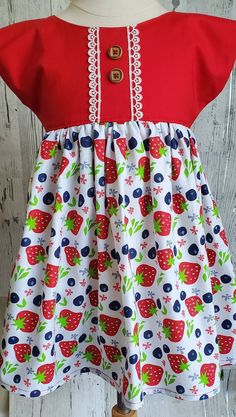 Perfect summer dress, describes the Strawberry Dress or tunic in beautiful patriotic colors!  With a red bodice top that ties in the back and a full gathered white skirt in strawberries and blueberries, this is perfect for a birthday party or 4th of July!   You can order this cutie as a Dress or in Tunic length, which is approximately 2 inches shorter, and can be worn with shorts, jeans, or pants.   Sizes are 12M - size 6 girls. Handmade in my smoke-free pet friendly home.   See sizing information in the photos. Berry Birthday Party, Blue Baby Dress, Berry Birthday, Patriotic Baby, Strawberry Dress, American Girl Doll Patterns, Bodice Top, Dress For Summer, Girls Handmade