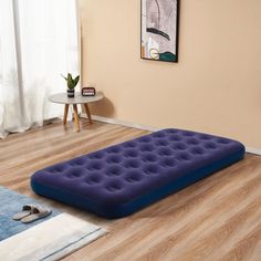 an inflatable mattress is sitting on the floor next to a table and chair