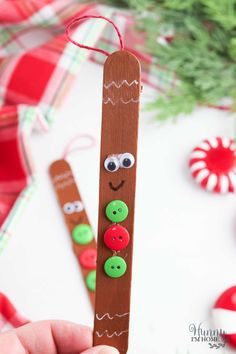 a hand holding a wooden stick with buttons on it and a christmas tree in the background