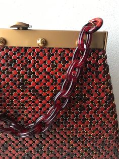 1970's Whiting & Davis metal mesh A frame handbag. Large mesh is done in a brick red and black snake-ish pattern. Soft matte gold frame with shiny gold decorative studs. 1" long tortoise plastic oval links form the handle. Lined in a purple-y brown faille with a single open side pocket. Comes with clear plastic printed bag. This bag is from 1976 which was the company's 100th year in business. Excellent condition. total height 14 1/4" height (bag) 7 1/2" length    top of bag 8"    bottom of bag 1 Red And Black Snake, Snake Pattern, Snake Patterns, Black Snake, Metal Mesh, Brick Red, Printed Bags, Matte Gold, Clear Plastic