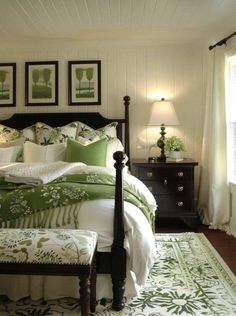 a green and white bed in a bedroom with pictures on the wall above it's headboard