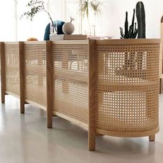 a wooden table topped with lots of potted plants next to a wall covered in wicker