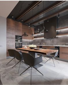 a modern kitchen with an island table surrounded by black chairs and pendant lights hanging from the ceiling