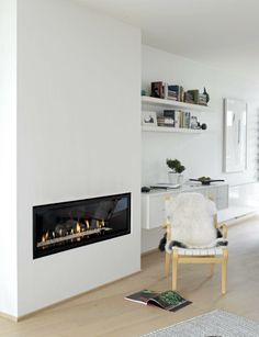 a living room with a fire place in the center and a chair next to it