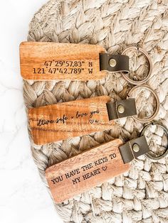 three wooden keychains with engraved names on them sitting on top of a woven mat