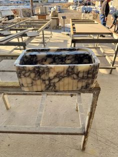 an outdoor area with tables and benches that are made out of marble blocks, in the background is a body of water