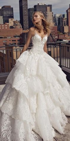 a woman in a white wedding dress standing on a balcony with the city skyline behind her