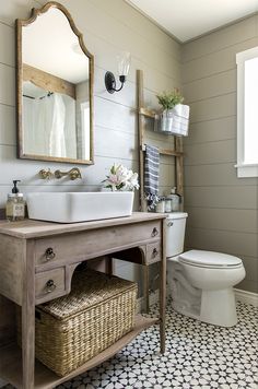 a white toilet sitting next to a sink in a bathroom under a wooden mirror mounted on a wall