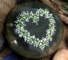 a heart shaped painted on a rock surrounded by other rocks and stones with plants growing out of it