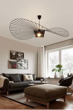 a living room with a couch, chair and ottoman under a light fixture in the ceiling