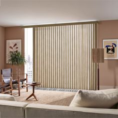 a living room with two couches and a large window covered in vertical blind blinds