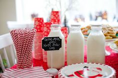 a table topped with milk bottles and plates filled with cookies next to candy canes